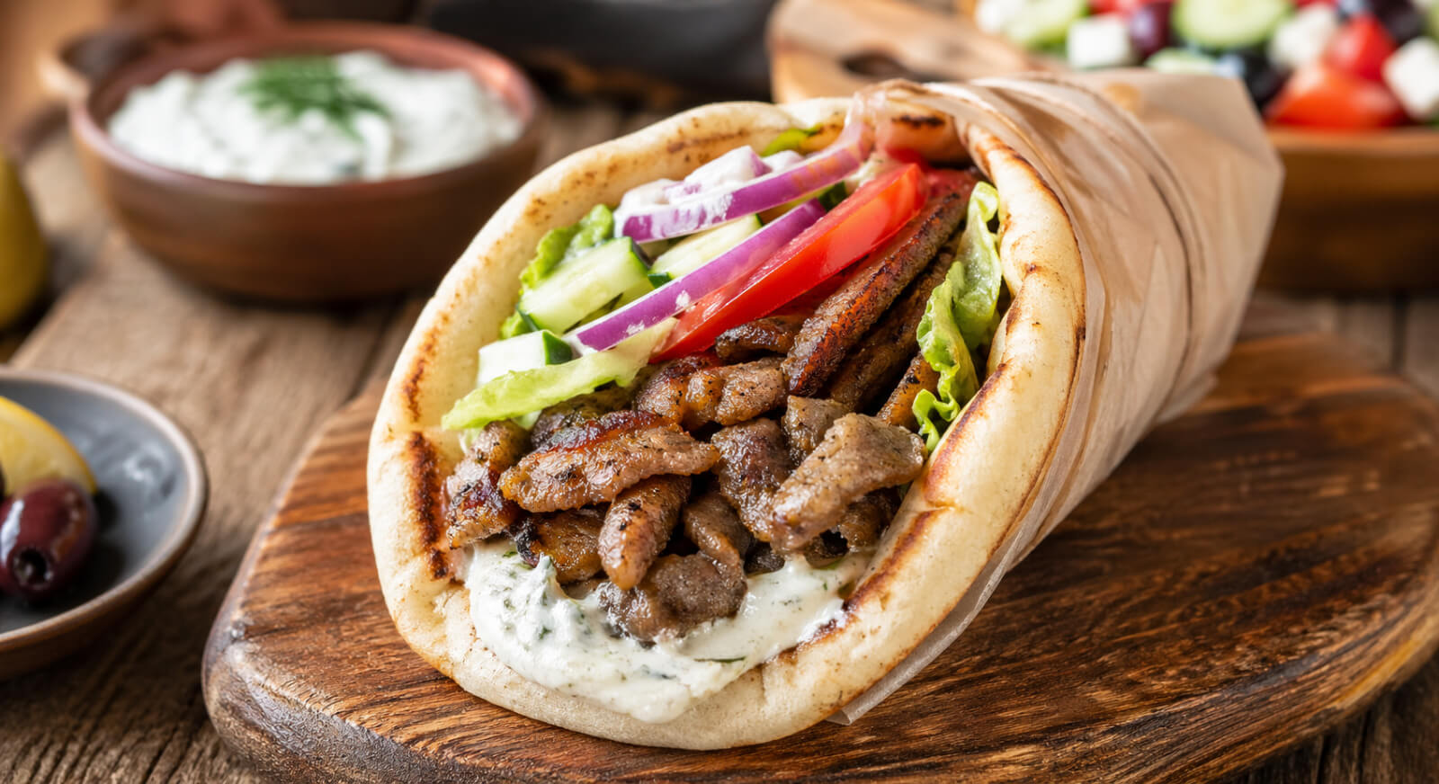 Easy pork gyro recipe with seasoned pork, warm pita, fresh vegetables, and tzatziki sauce
