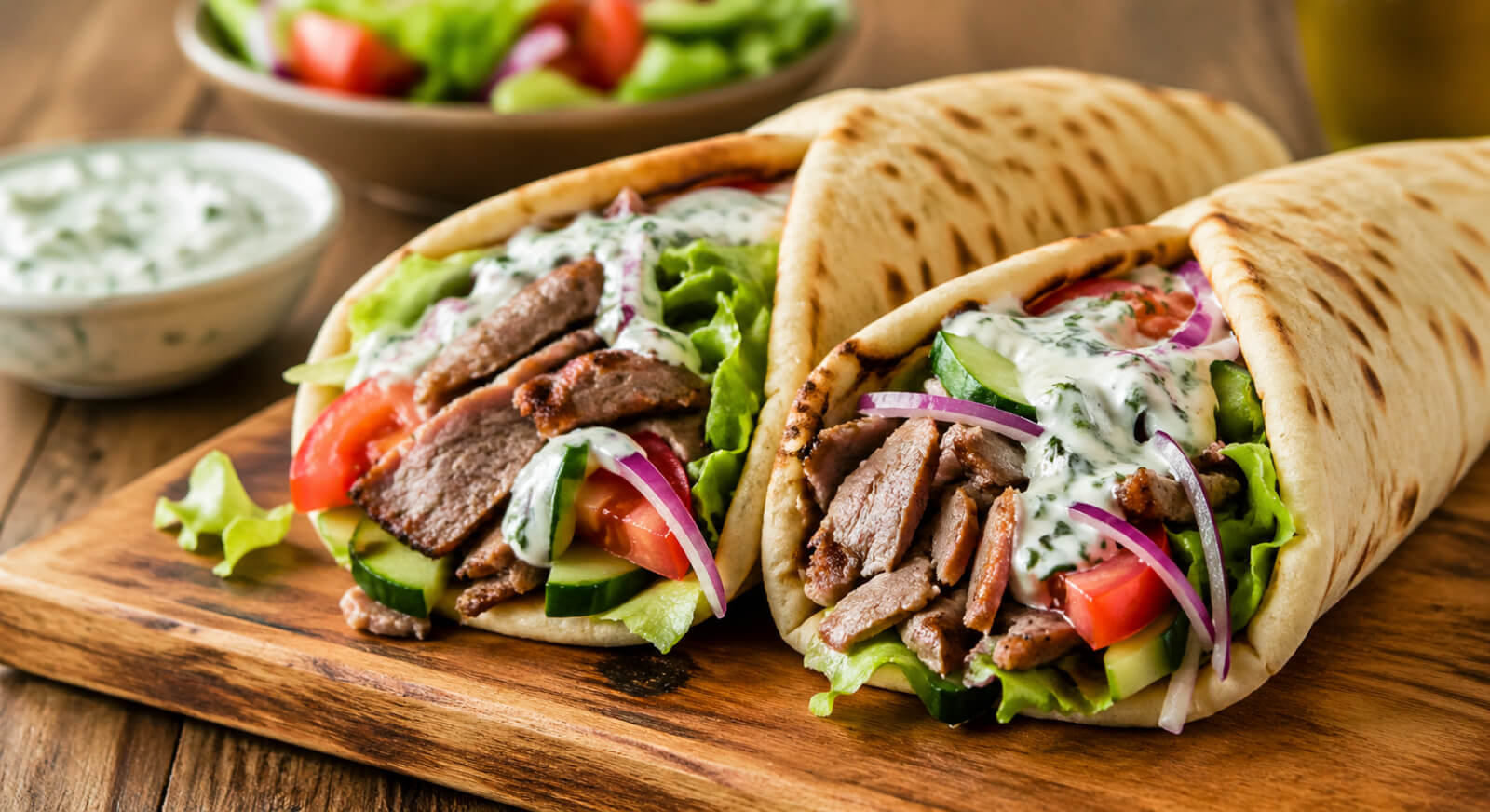 Lamb gyros with tzatziki sauce, tomatoes, red onion, lettuce, and warm pita bread