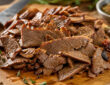 Sliced lamb gyro meat on a cutting board for homemade lamb gyros