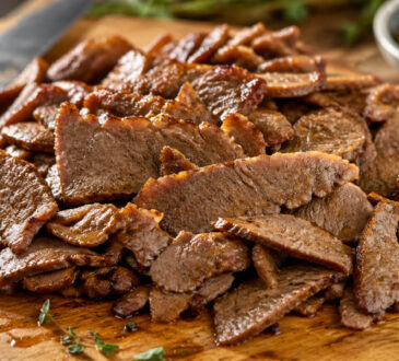 Sliced lamb gyro meat on a cutting board for homemade lamb gyros