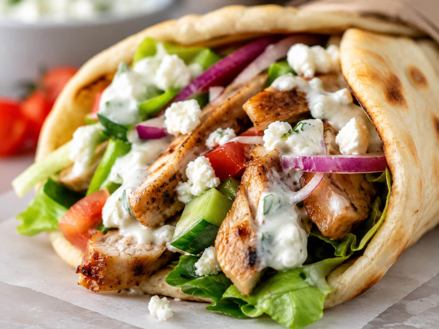 Chicken gyro wrap with grilled chicken, warm pita, cucumber, tomato, red onion, lettuce, feta, and tzatziki sauce