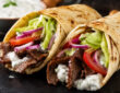 American gyro recipe with beef and lamb gyro meat, warm pita, lettuce, tomato, onion, and creamy gyro sauce