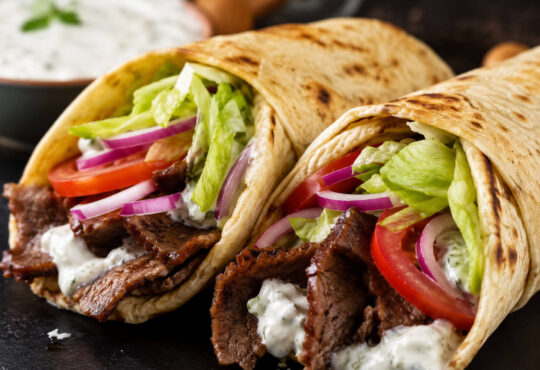 American gyro recipe with beef and lamb gyro meat, warm pita, lettuce, tomato, onion, and creamy gyro sauce