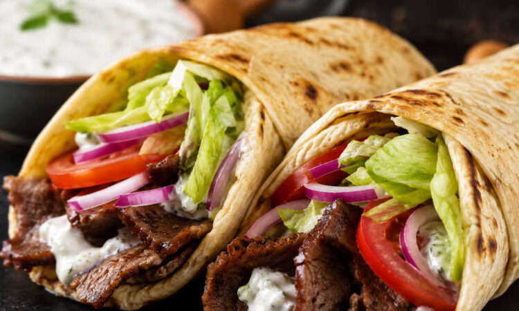 American gyro recipe with beef and lamb gyro meat, warm pita, lettuce, tomato, onion, and creamy gyro sauce