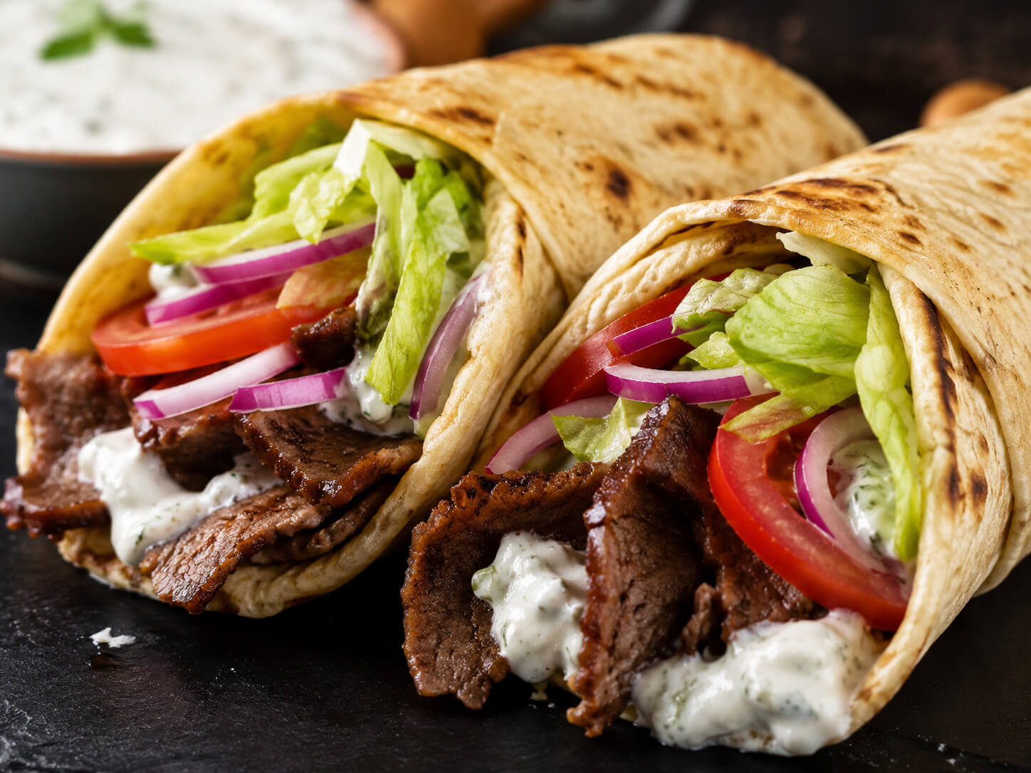 American gyro recipe with beef and lamb gyro meat, warm pita, lettuce, tomato, onion, and creamy gyro sauce
