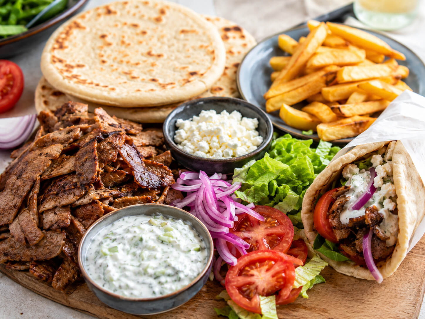 American gyro toppings with sliced gyro meat, lettuce, tomato, onion, cucumber, and creamy gyro sauce