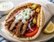 Authentic Greek gyros recipe with seasoned meat, warm pita, tomatoes, onions, fries, and tzatziki sauce