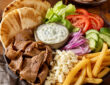 Gyro toppings with pita bread, sliced gyro meat, lettuce, tomato, cucumber, red onion, feta, fries, and tzatziki sauce