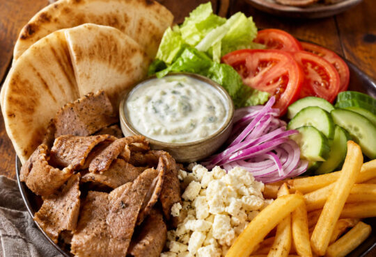 Gyro toppings with pita bread, sliced gyro meat, lettuce, tomato, cucumber, red onion, feta, fries, and tzatziki sauce