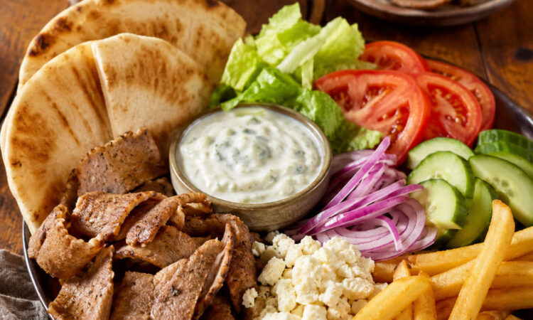 Gyro toppings with pita bread, sliced gyro meat, lettuce, tomato, cucumber, red onion, feta, fries, and tzatziki sauce