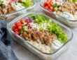 Chicken gyro meal prep bowls with Greek chicken, rice, cucumber, tomatoes, red onion, lettuce, and tzatziki sauce