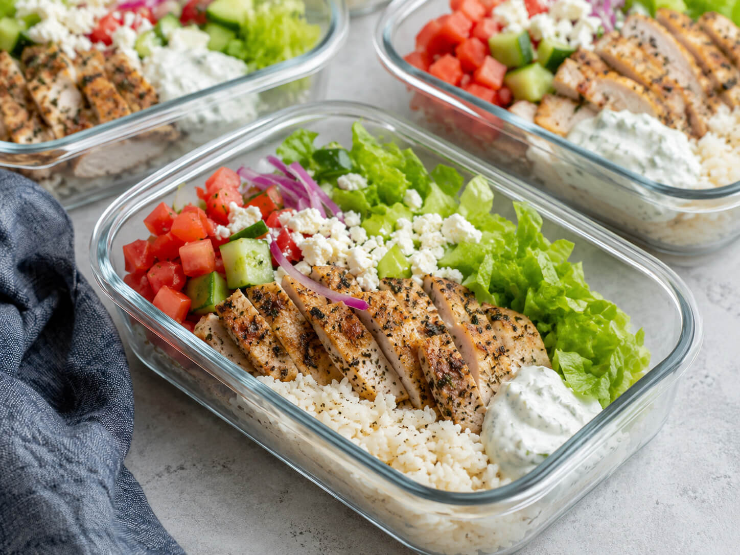Chicken gyro meal prep bowls with Greek chicken, rice, cucumber, tomatoes, red onion, lettuce, and tzatziki sauce