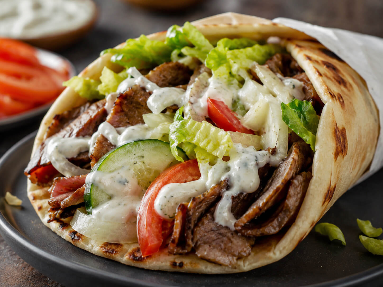 Gyro fillings and sauces with pita bread, sliced meat, vegetables, feta, fries, and tzatziki sauce