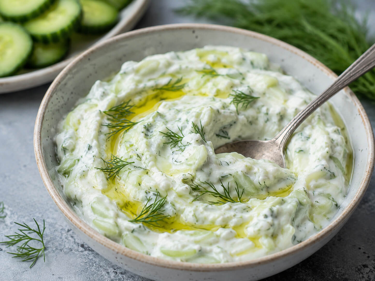 Homemade tzatziki sauce in a bowl with cucumber, garlic, lemon, dill, and olive oil