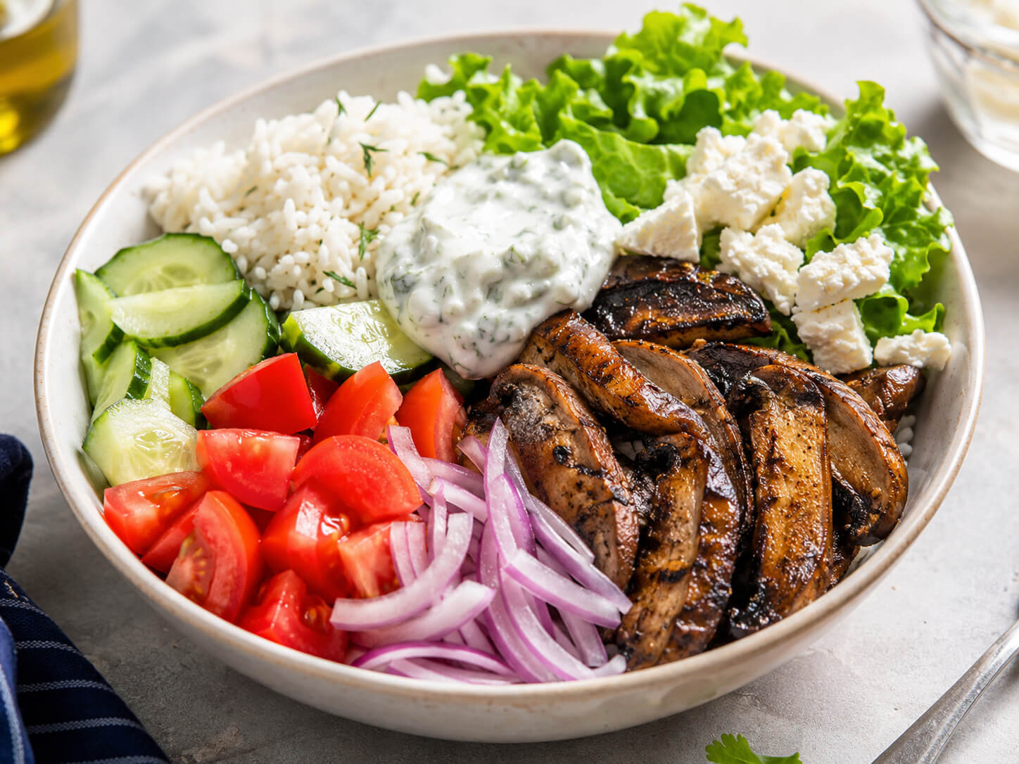 Vegetarian gyro bowl with portobello mushrooms, rice, cucumber, tomatoes, red onion, lettuce, feta, and tzatziki sauce